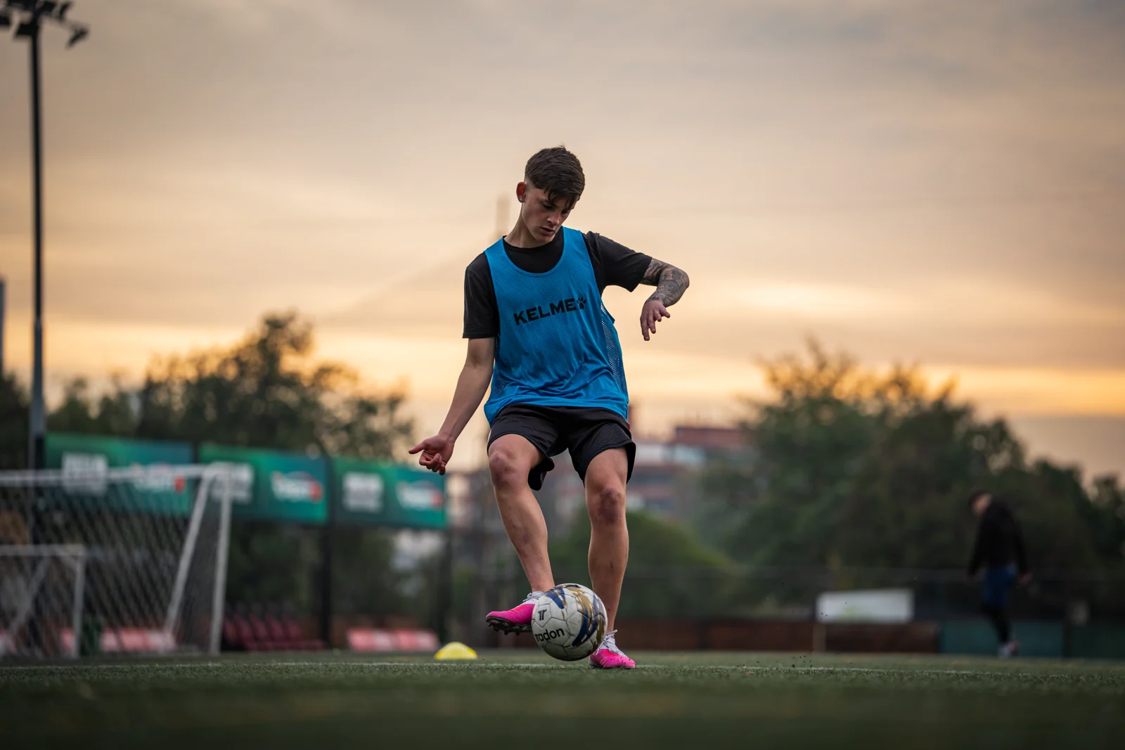 Futbolista con peto azul controlando el balón durante un entrenamiento en cancha